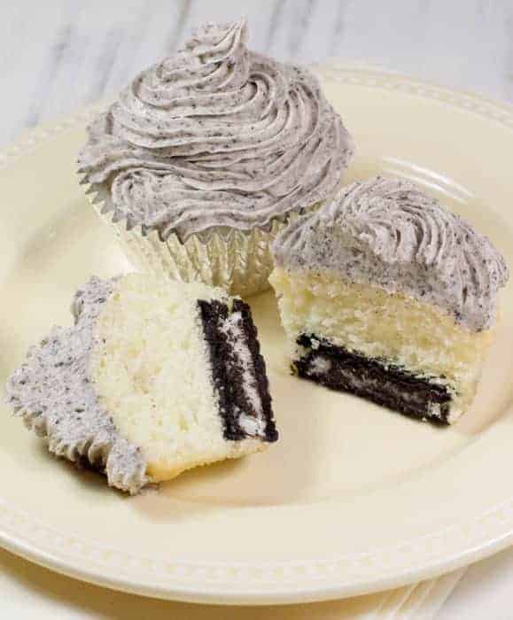 Two Cake Mix Cookies and Cream Cupcakes on a light yellow plate with the one in the front cut open