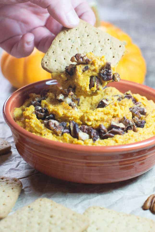 Dipping graham cracker into hummus in a bowl