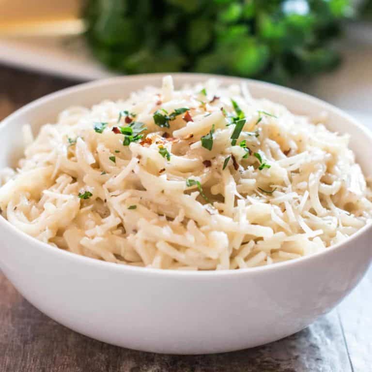 Front view of cacio e pepe in a white bowl with crushed red pepper flakes and parsley