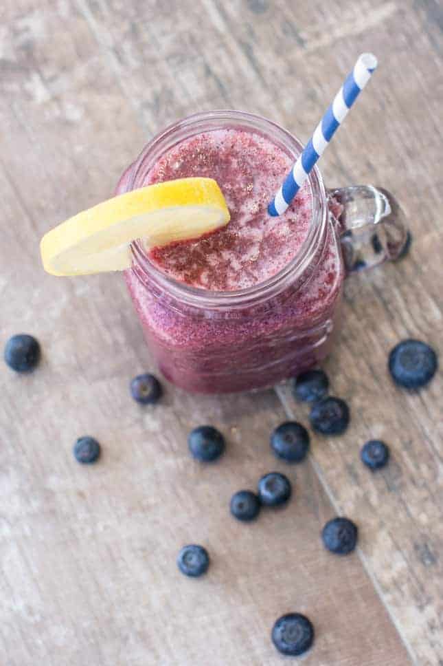 overhead of apple blueberry lemon smoothie in mason jar with straw and blueberries on table