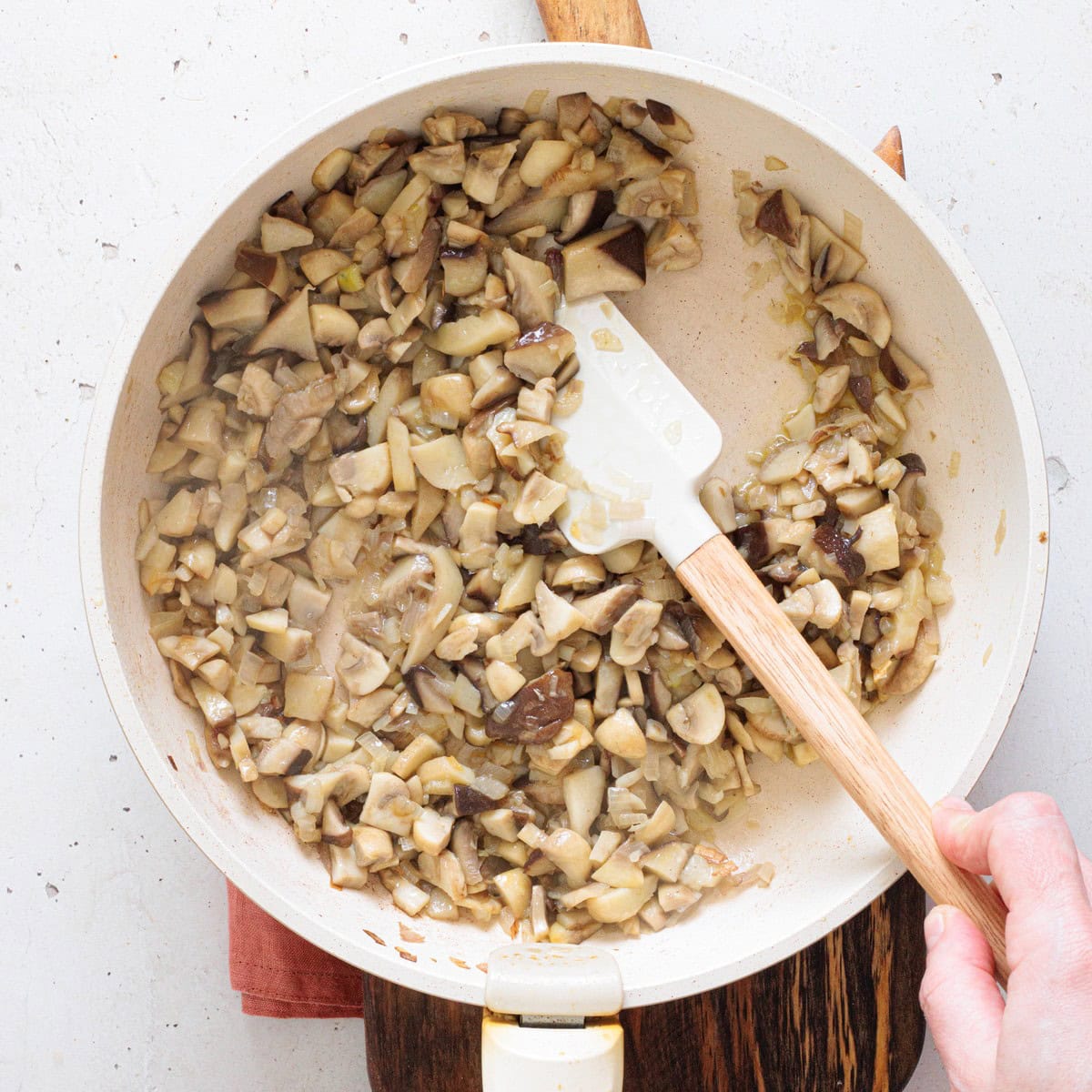 Saut&eacute;ed mushrooms being stirred in a pan until golden and softened for the creamy mushroom dip filling