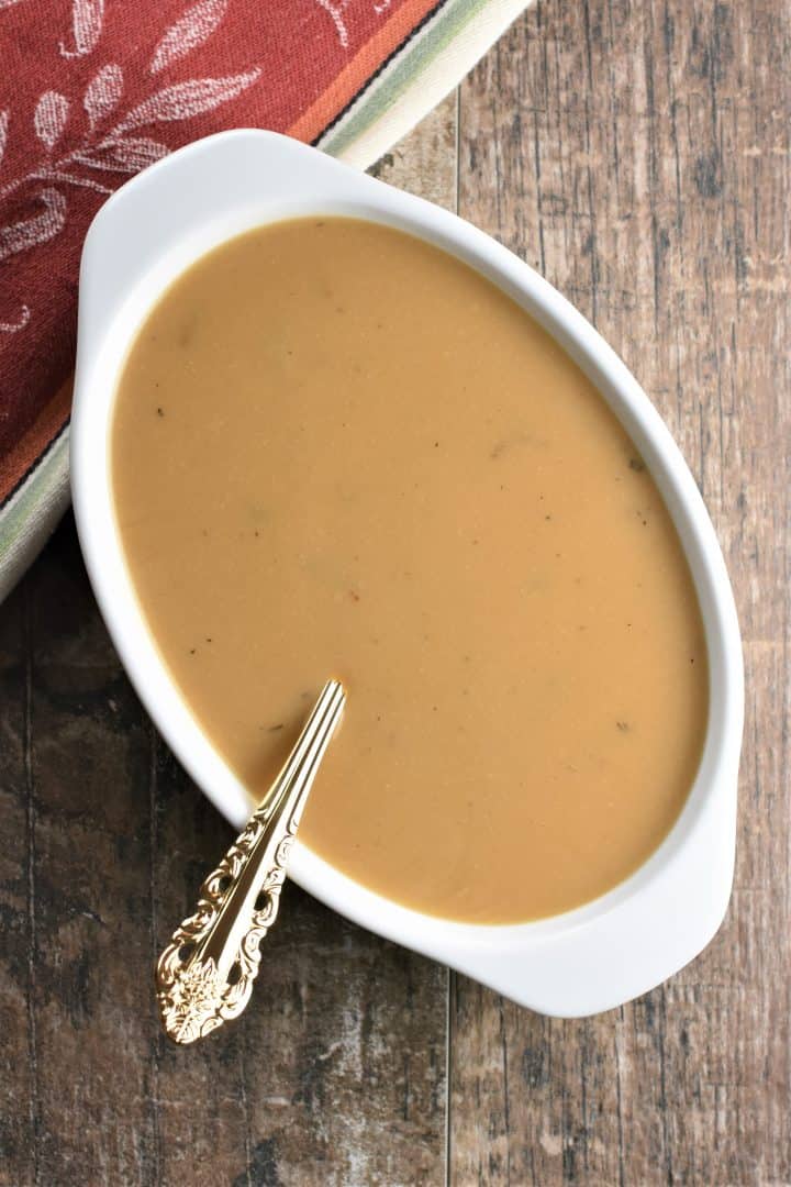 overhead of gravy in a white serving dish with a ladle in it