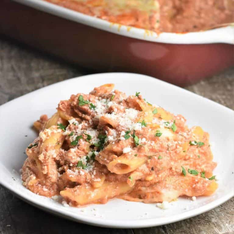 Serve the baked ziti on a white plate with grated cheese and parsley.