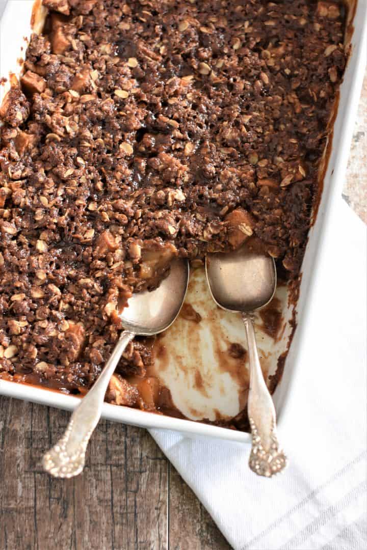 overhead of baked apple crisp in a dish with two serving spoons in it