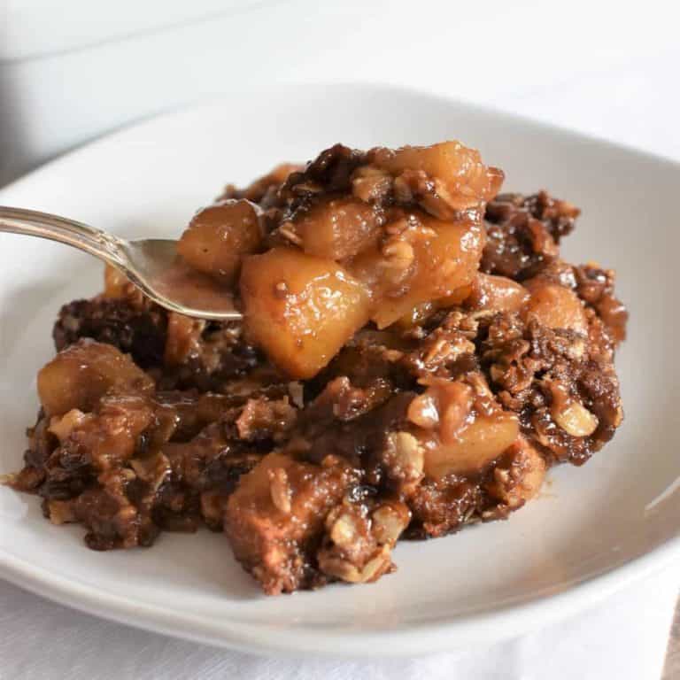Vegan apple crisp being scooped up on a fork from a plate