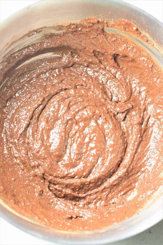 Cocoa powder mixed into wet and dry ingredients in a mixing bowl