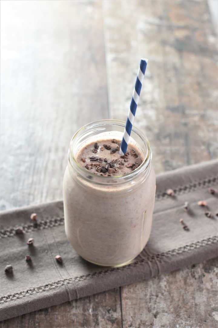 smoothie in mason jar with a straw and cacao nibs on top