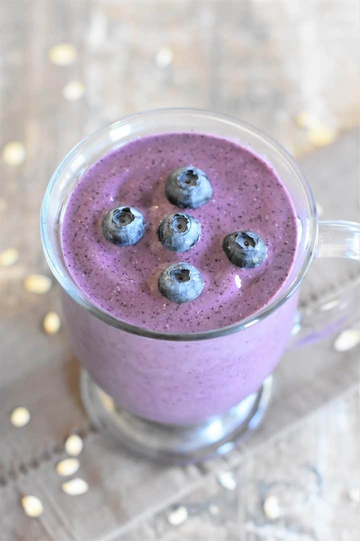 Blueberry pie smoothie in a glass mug with blueberries on top