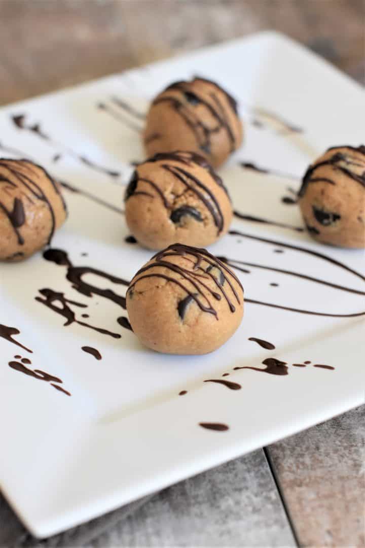 front view of cookie dough balls covered with drizzle on a white plate