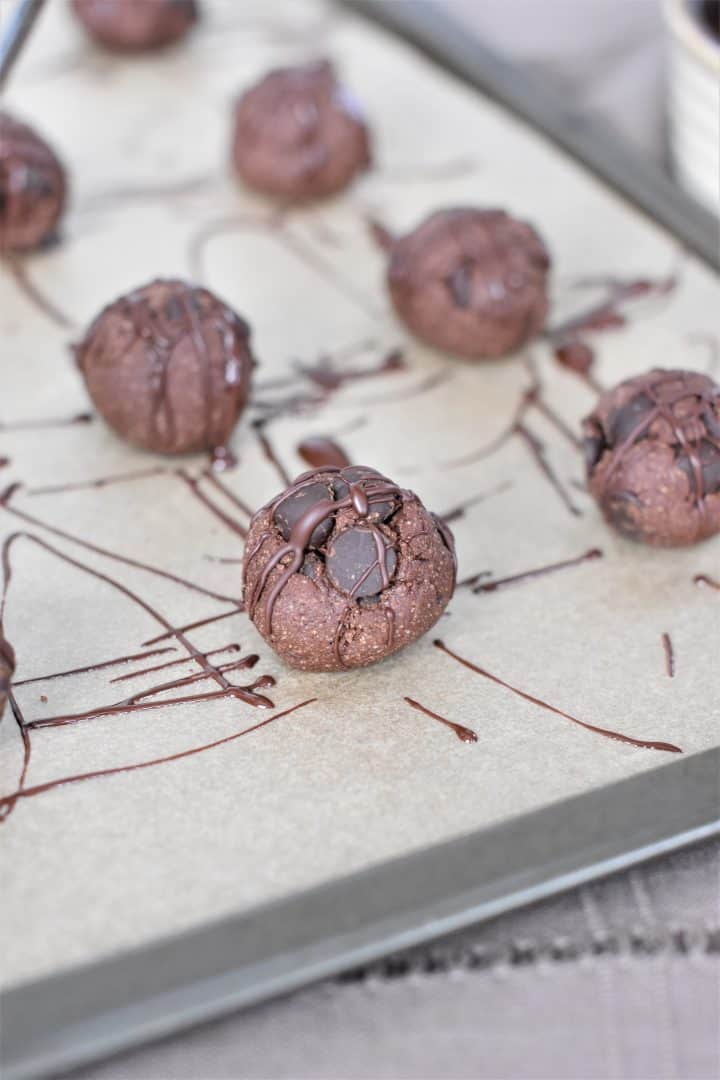 cookie bites on parchment paper after chocolate was drizzled on top