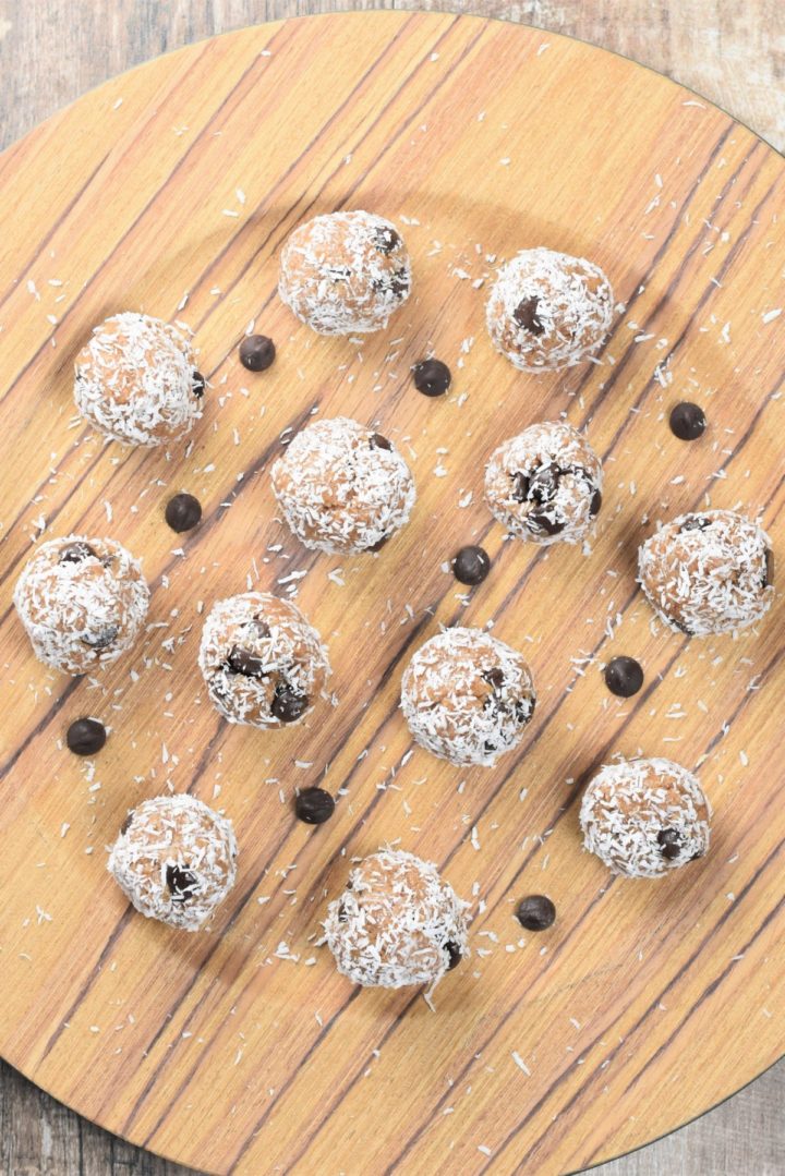overhead of dough bites on a wooden plate with some chocolate chips around