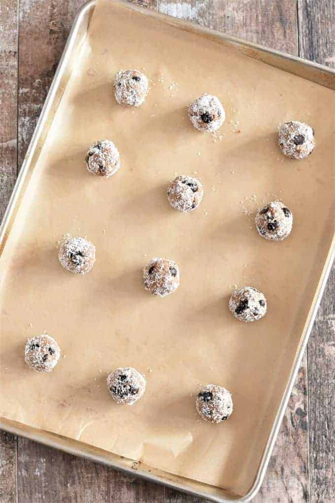 Almond butter balls covered in coconut on a baking sheet