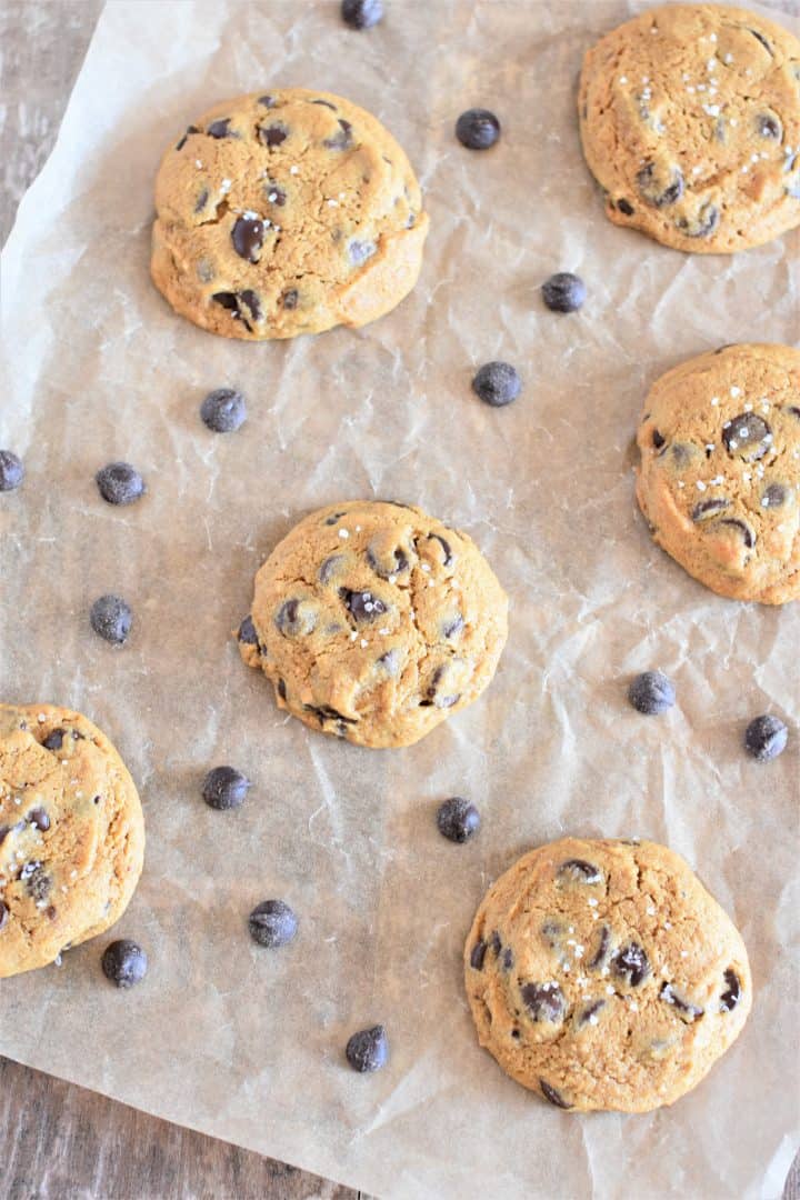 overhead of some cookies on parchment with chocolate chips around
