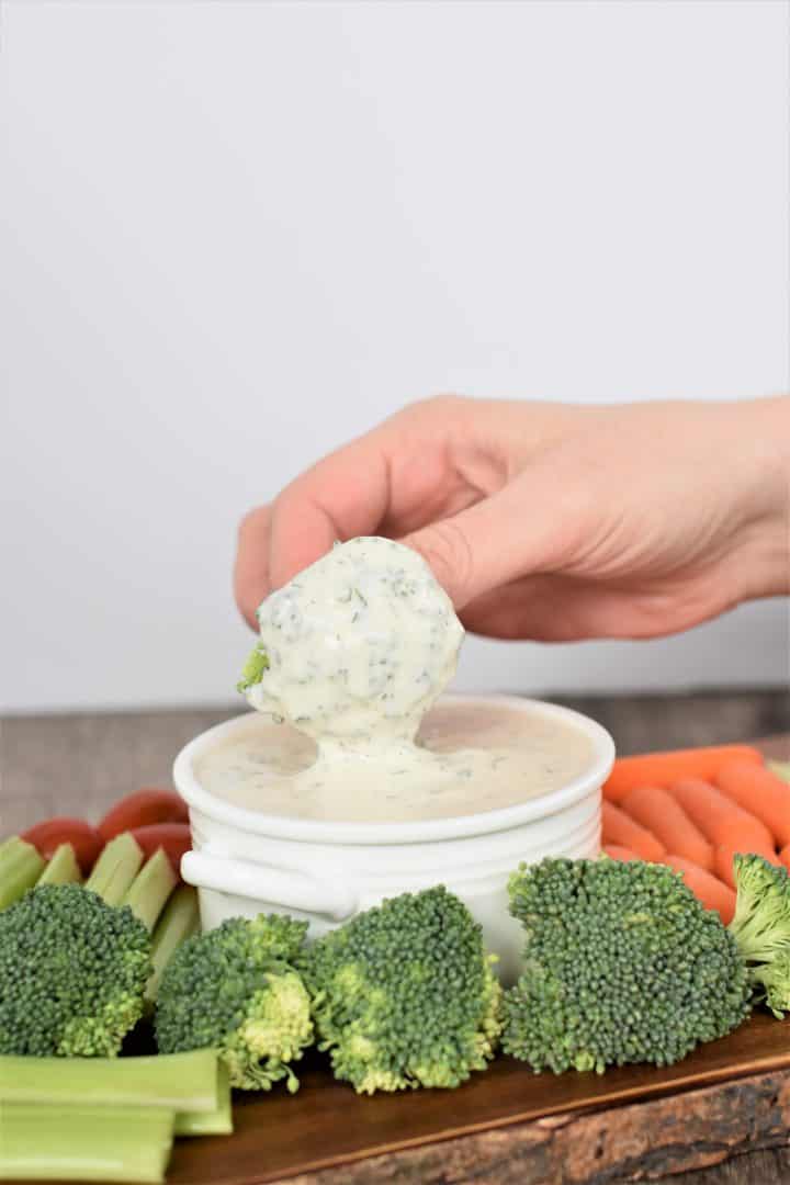 Dipping broccoli into vegan ranch dressing