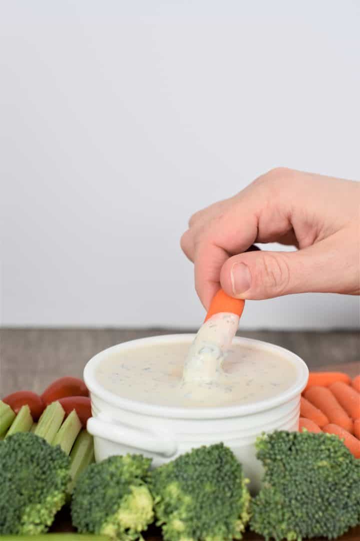 Dipping a carrot into vegan ranch dressing