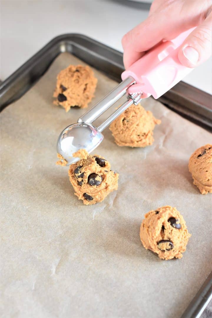 Scooping cookie dough on a tray with parchment paper