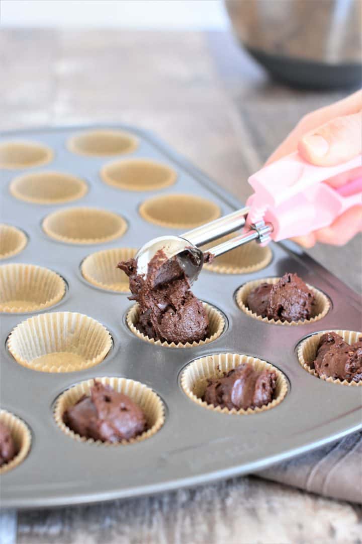 Scooping brownie batter into a mini muffin tin