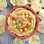 overhead of hummus in bowl with tortilla chips around it