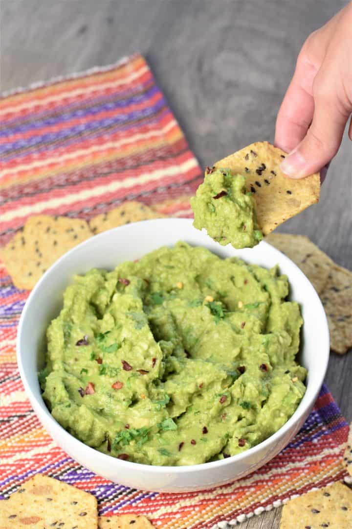 Scooping guacamole on a chip from the bowl