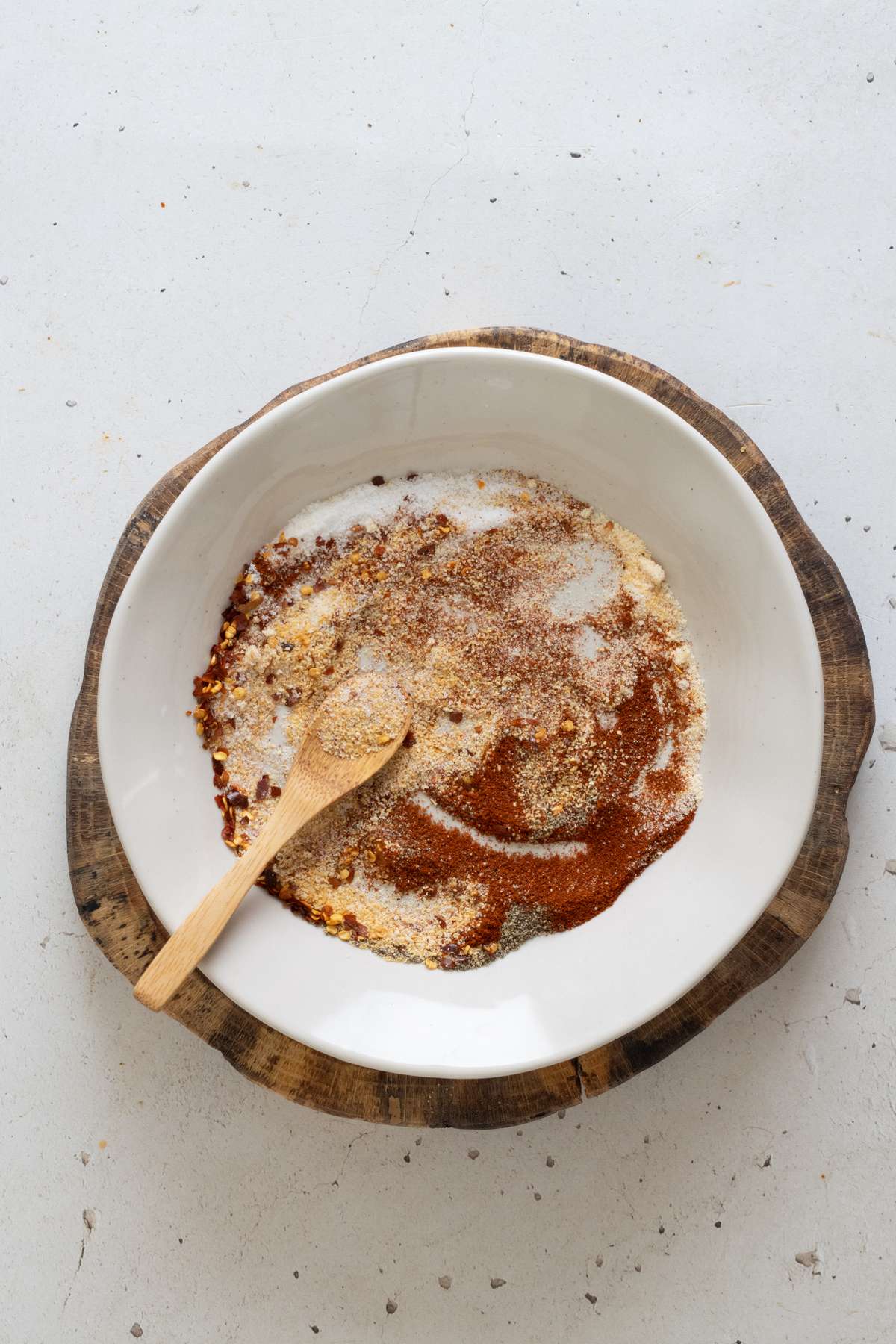 Fully blended homemade guacamole seasoning mix in a white bowl with a wooden spoon on a wooden board