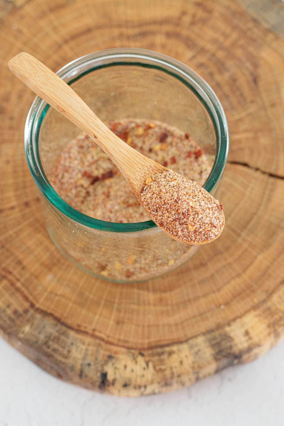 Close-up of homemade guacamole seasoning mix stored in a glass jar with a small wooden spoon