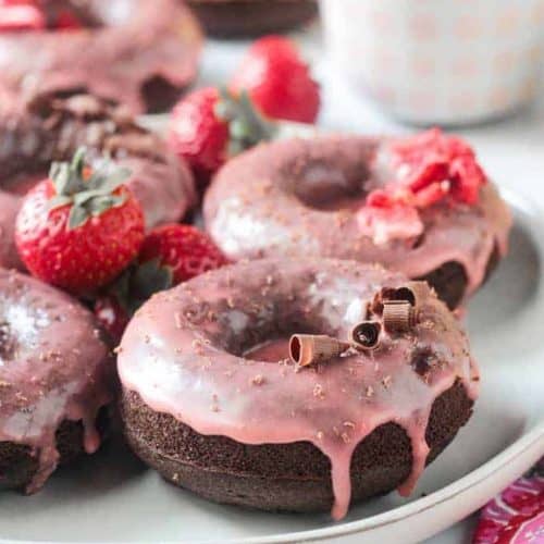 doughnuts on a white dish garnished with chocolate shavings and strawberries