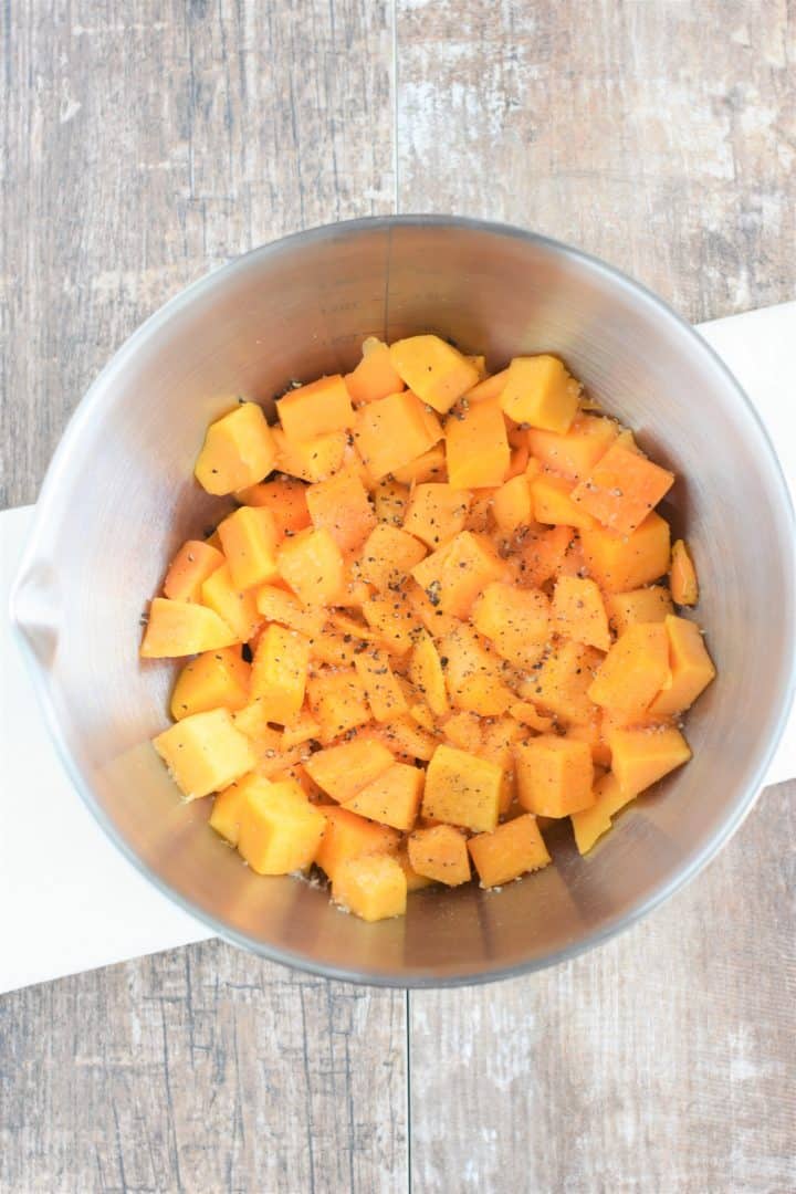 Olive oil, salt and pepper added to butternut squash chunks in mixing bowl