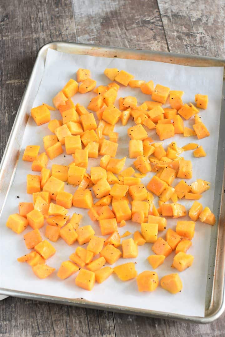 Butternut squash uncooked on baking sheet with parchment paper