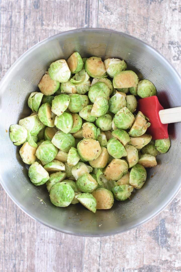 Brussels sprouts in mixing bowl with olive oil, balsamic vinegar, salt and pepper mixed in