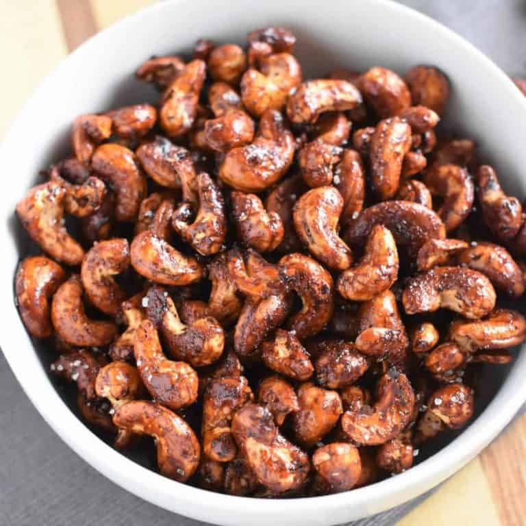 overhead of cashews in a white bowl on a wooden board
