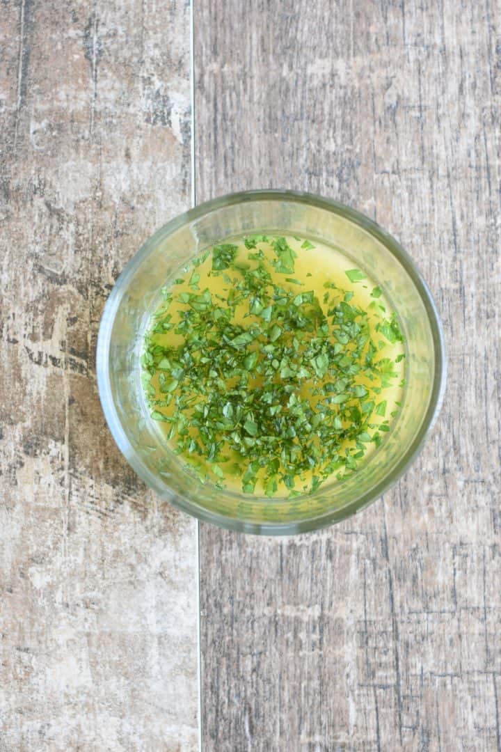 Garlic-infused olive oil, parsley and salt added to bowl of melted butter