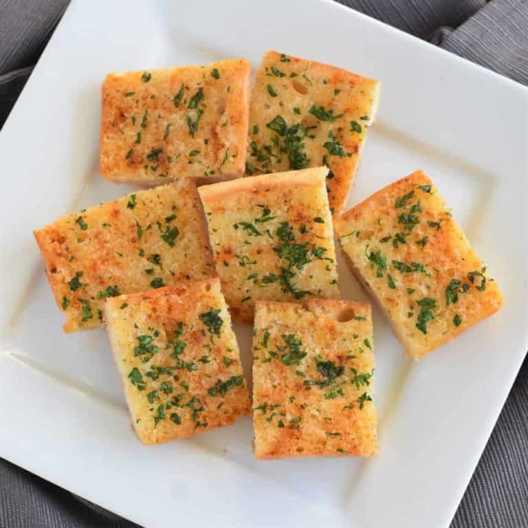 overhead view of cut pieces of garlic bread on a white plate