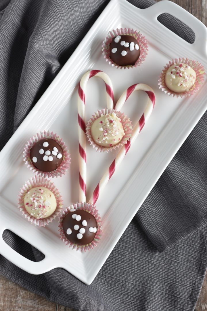 Truffles on a white serving dish with two candy canes forming a heart around one of them