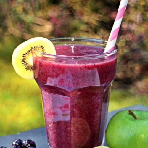 front view of fruit smoothie in a glass with a straw.