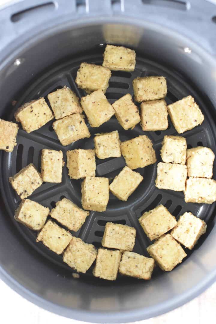 Cooked tofu in air fryer basket after air frying