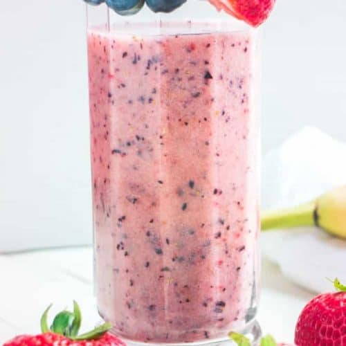 front view of banana strawberry blueberry smoothie in a tall glass.