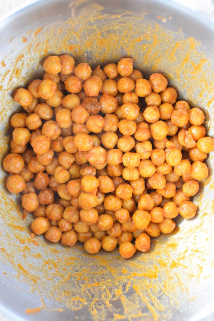 Chickpeas mixed with Buffalo seasoning in mixing bowl