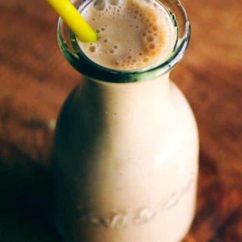 cardamom smoothie in old fashioned milk bottle with a straw.