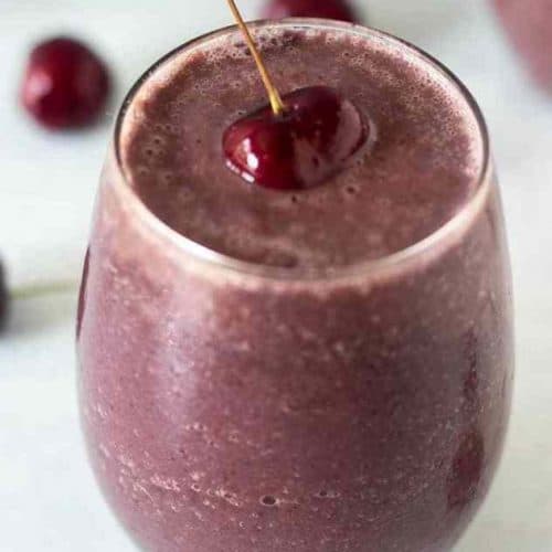 cherry smoothie in a glass with cherry on top.