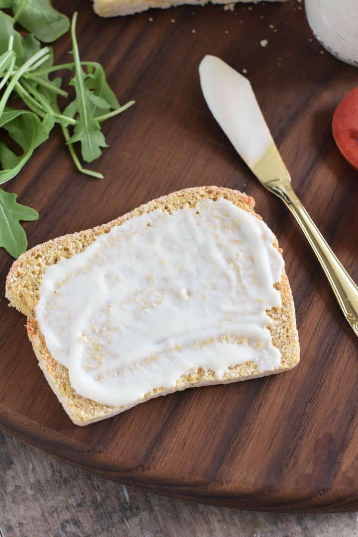 Mayo spread on a piece of gluten-free bread with spreading knife next to it