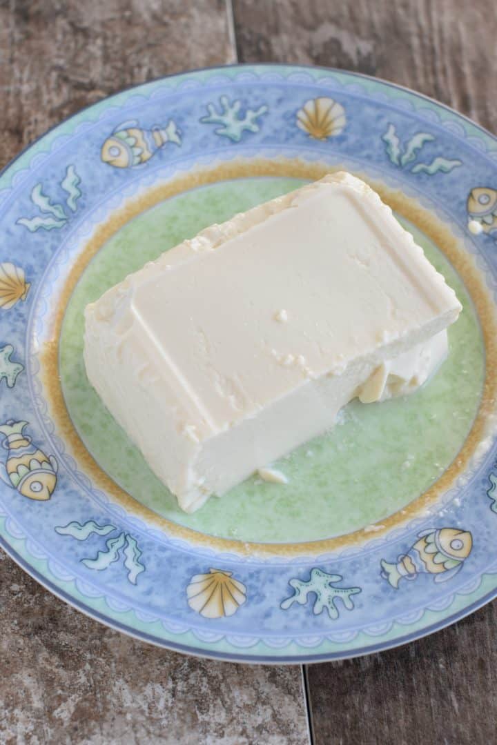 Half of a block of silken tofu on a plate to drain