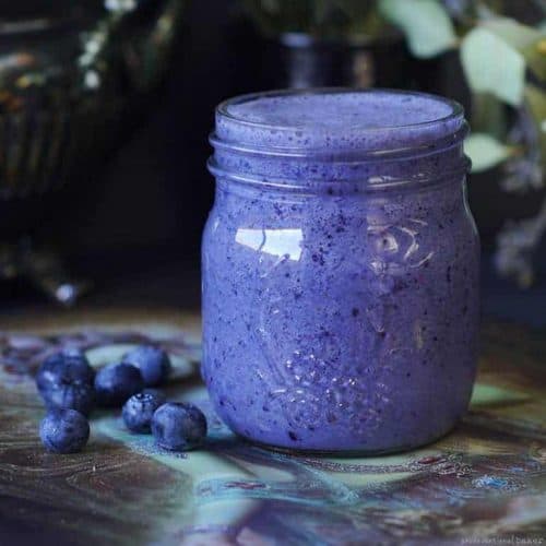 blueberry tahini smoothie in a mason jar with blueberries next to it.