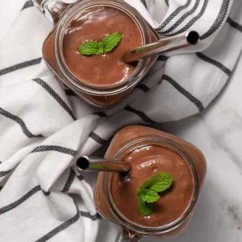 overhead of two chocolate avocado smoothies with straws.