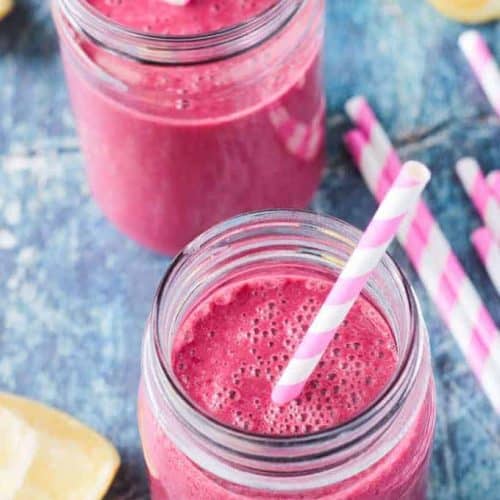 overhead of two strawberry beet smoothies in mason jars with straws.