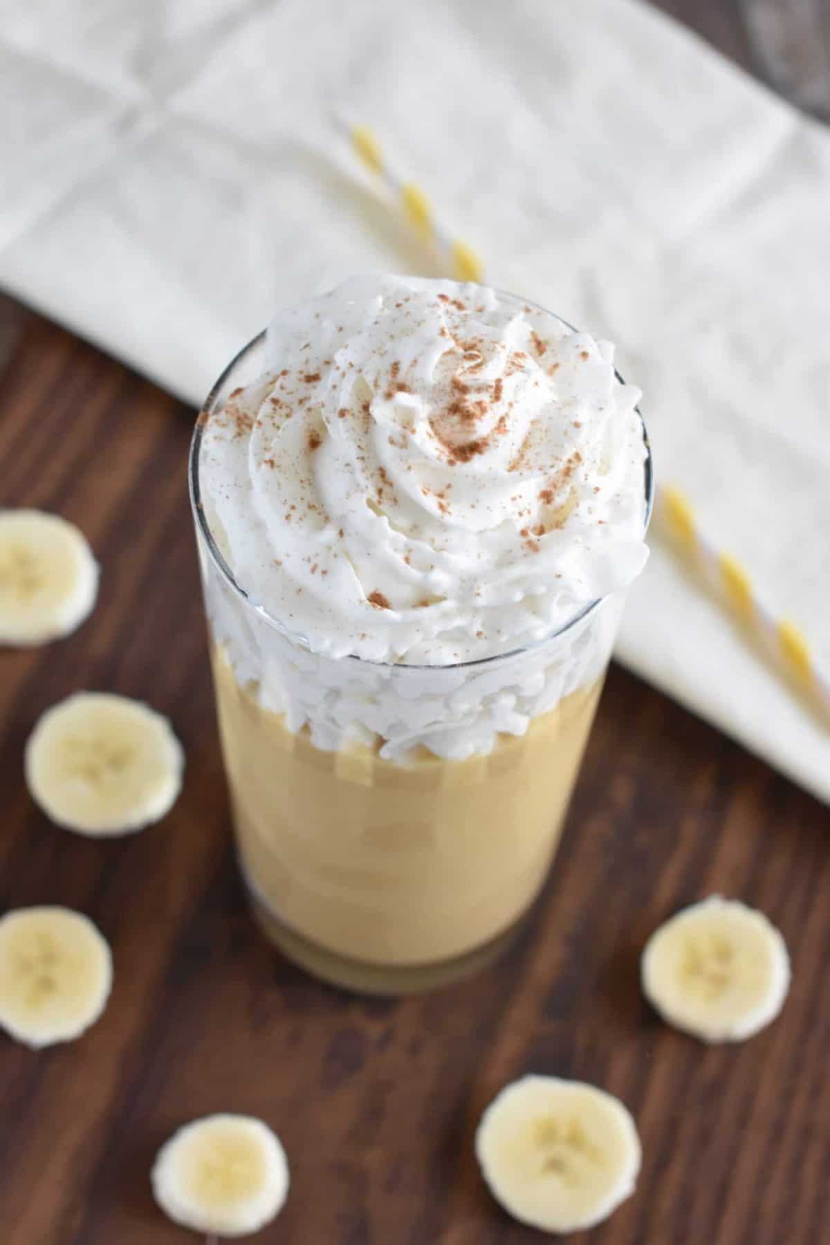 overhead of apple banana smoothie with vegan whipped topping and cinnamon