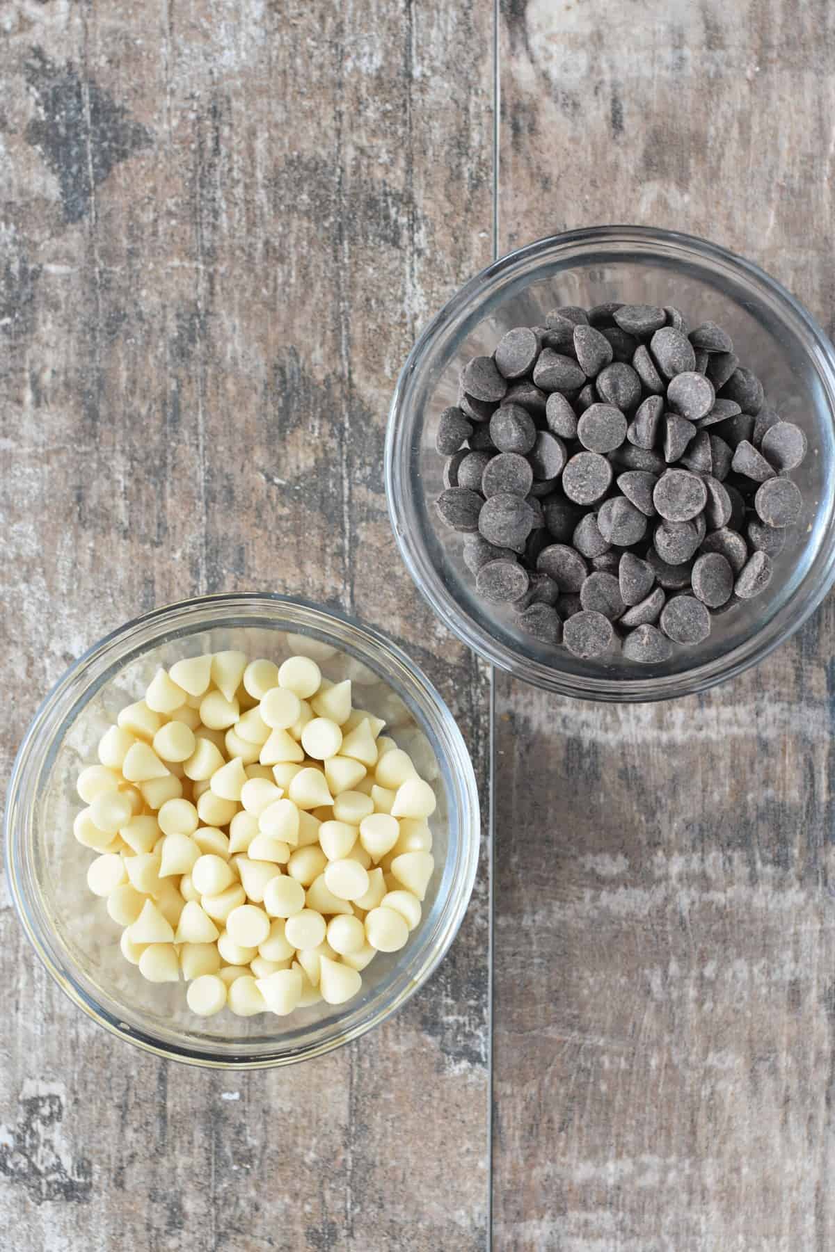 Dark chocolate chips and white chocolate chips in two small bowls