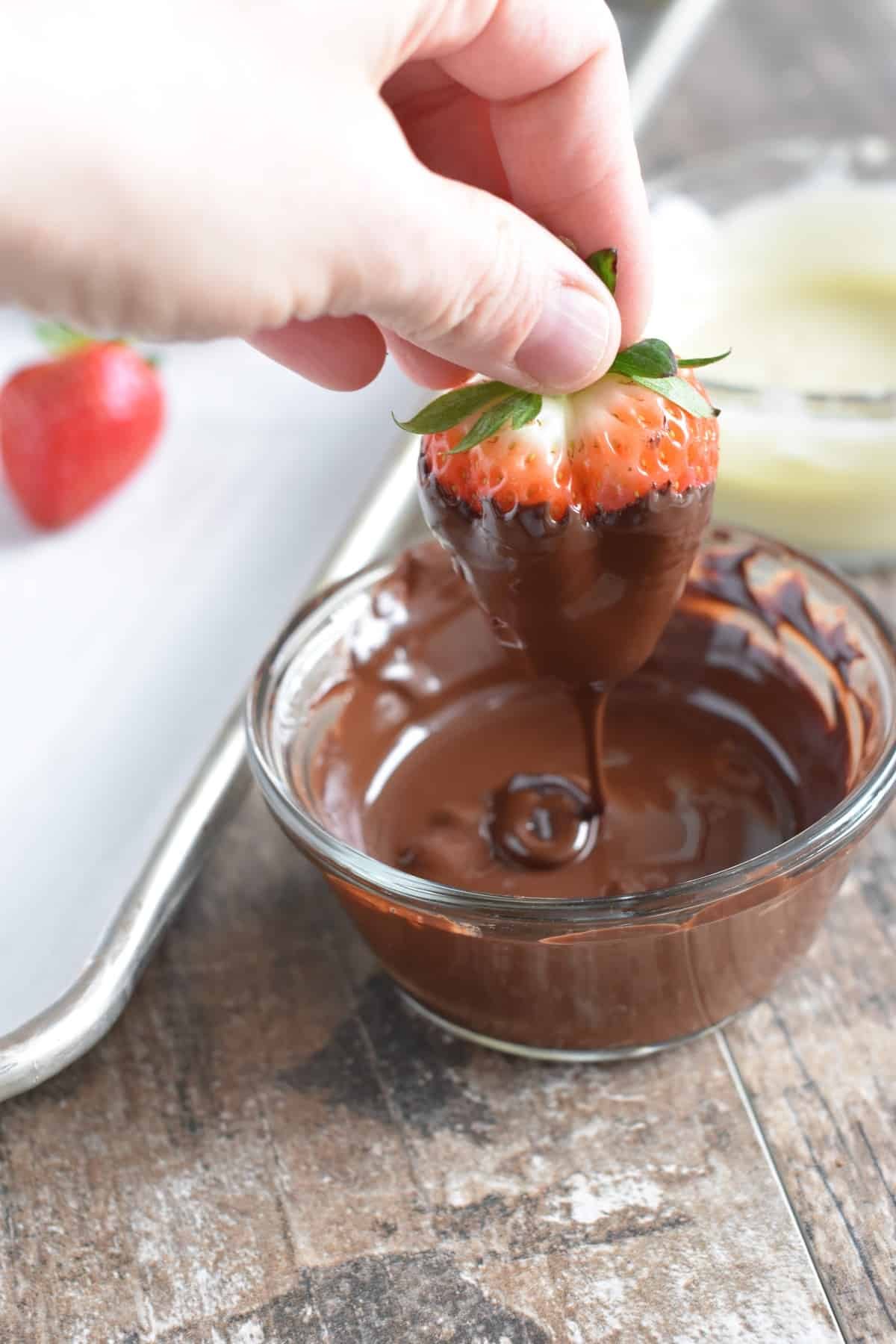 Dipping a strawberry into melted dark chocolate