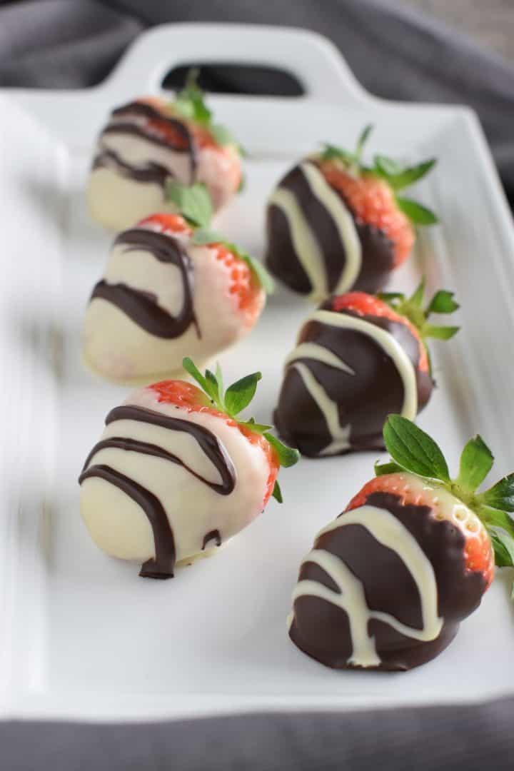 front view of chocolate dipped strawberries on white serving platter