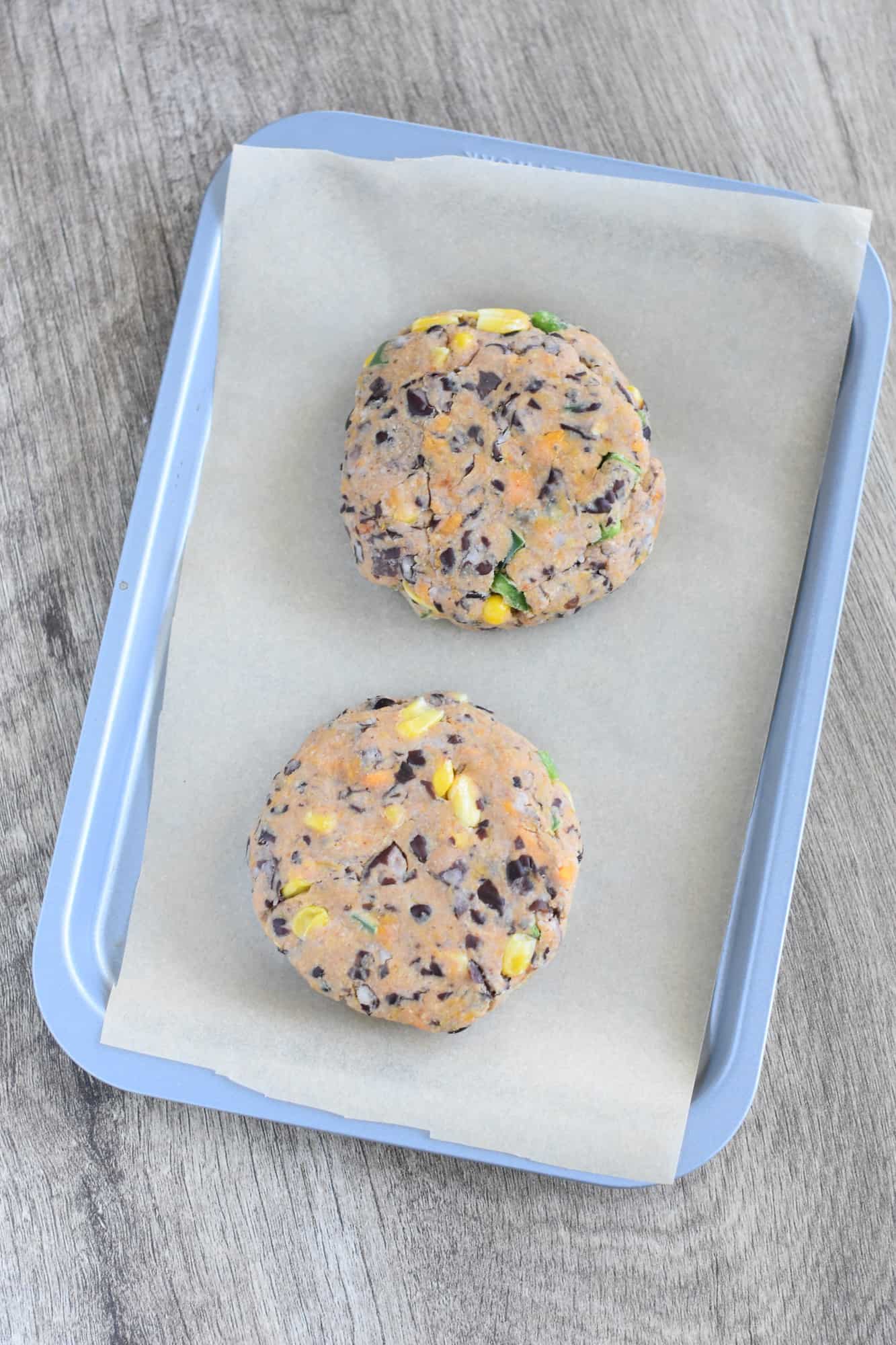 formed sweet potato black bean burgers on a parchment-lined baking sheet after freezing for one hour