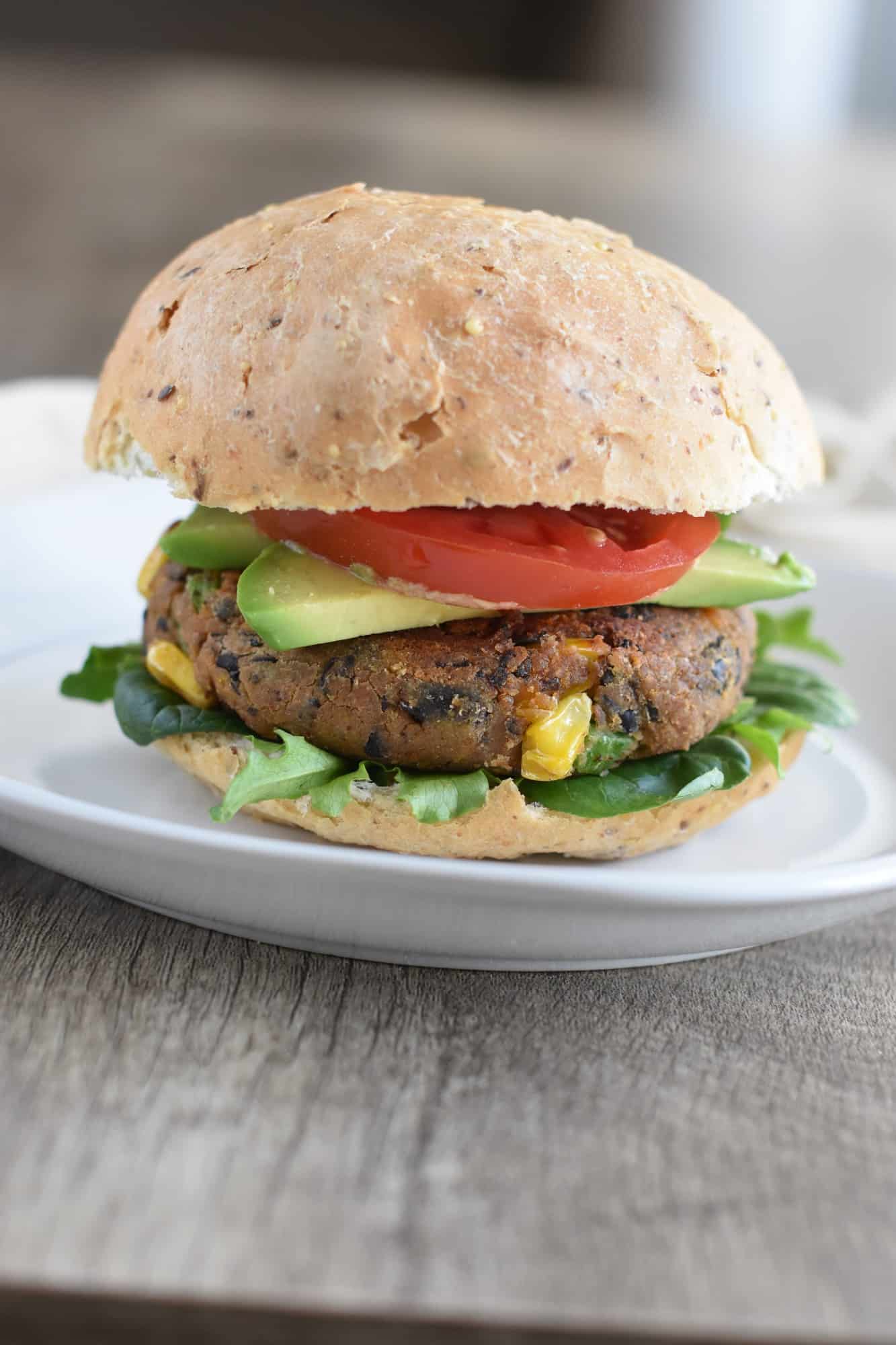 burger on a bun with tomato, avocado and lettuce